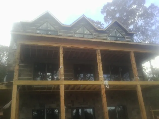 Dormers and porch framing on a large log home under construction — Roof Coating work by our crew in Seneca