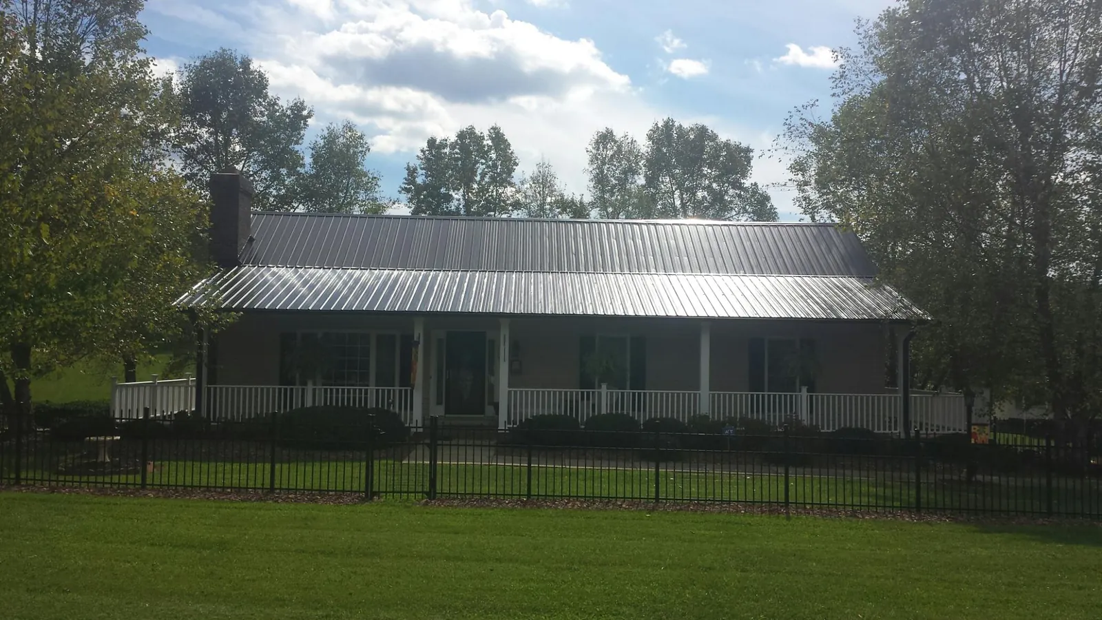 Gray metal roof on a brick ranch with a full width front porch — Gutter Guard Installation work by our crew in Seneca