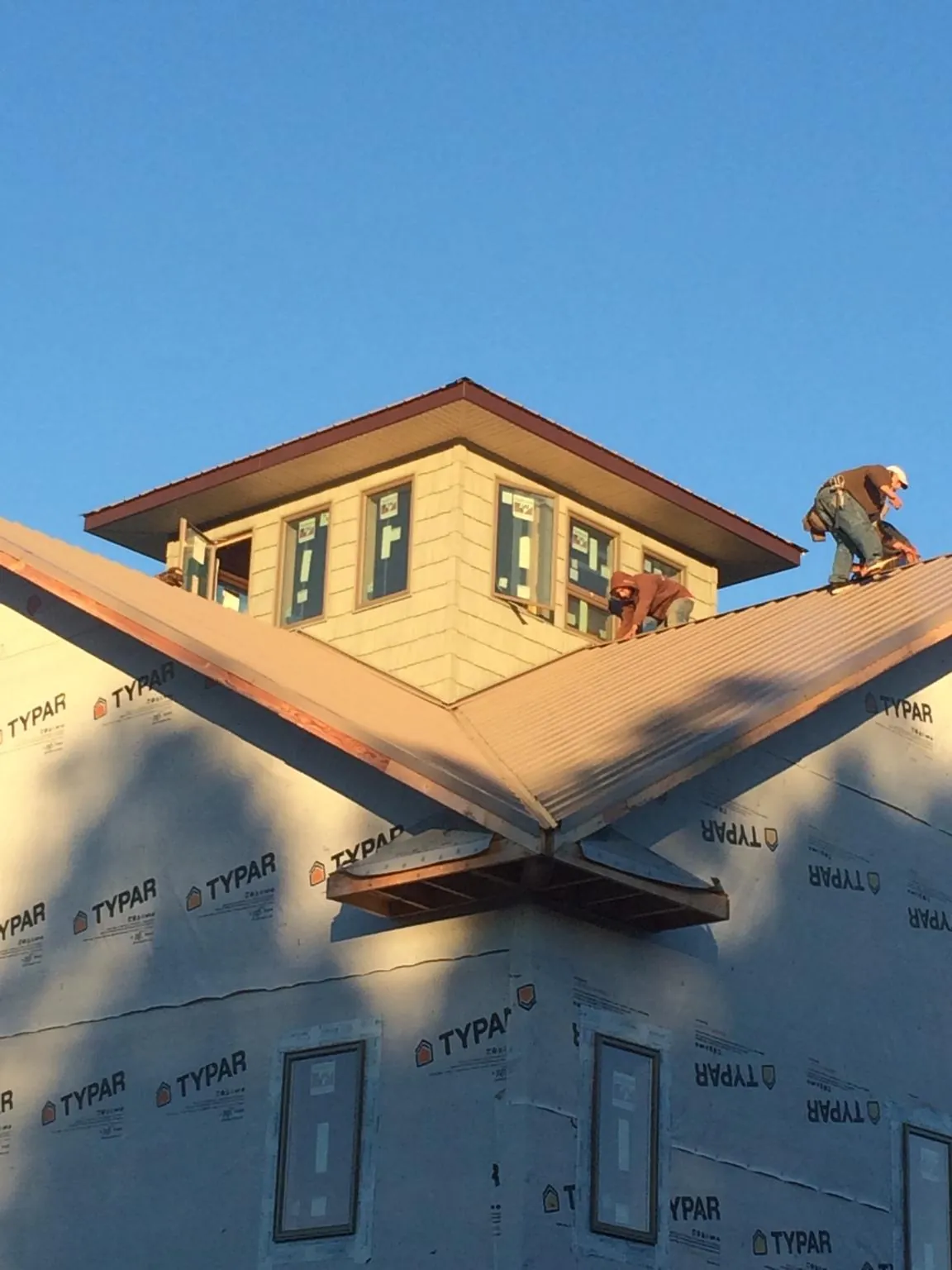 Roofers working around a rooftop cupola on a new metal roof at sunset — Roof Waterproofing in Seneca by Roofing Brothers